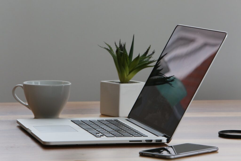 Laptop und iPhone liegen auf einem Holztisch