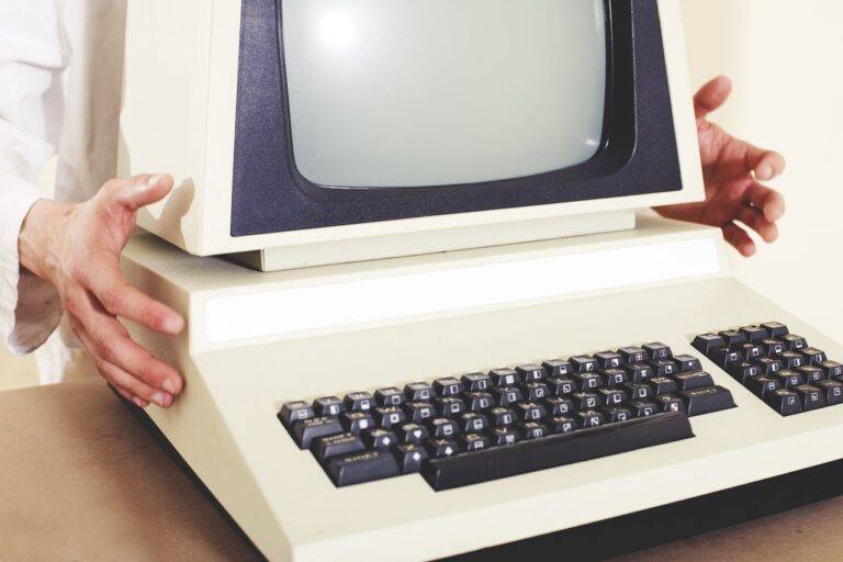 Person hält einen vintage Computer mit einem großen CRT-Monitor und einer Tastatur in Beige.