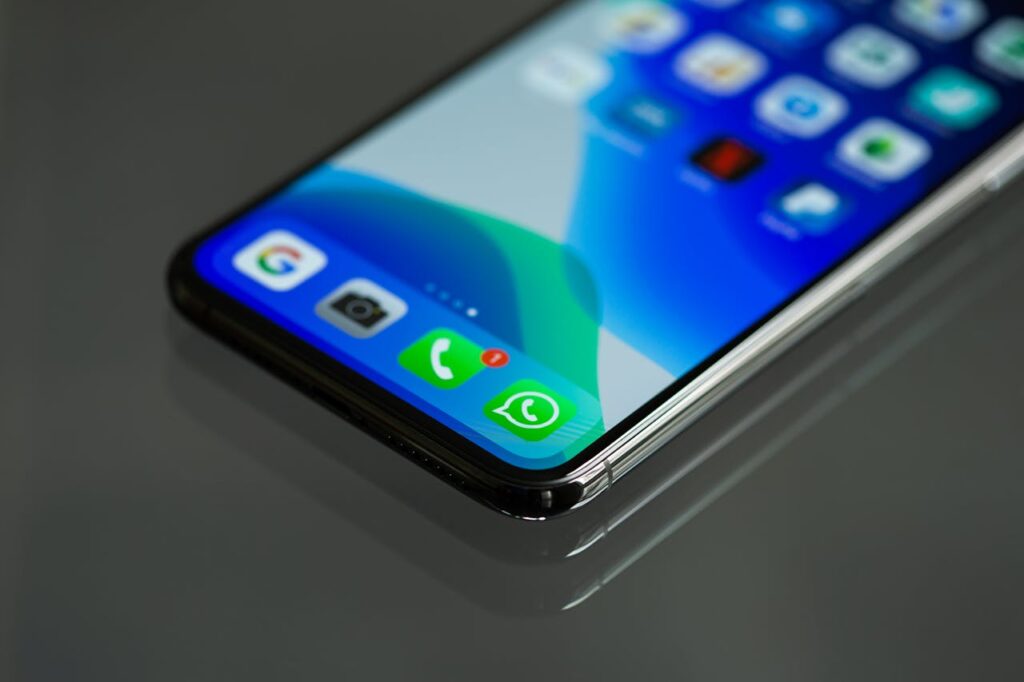 Nahaufnahme eines modernen Smartphones mit geöffnetem Startbildschirm, auf dem unter anderem das grüne WhatsApp-Symbol deutlich sichtbar ist.